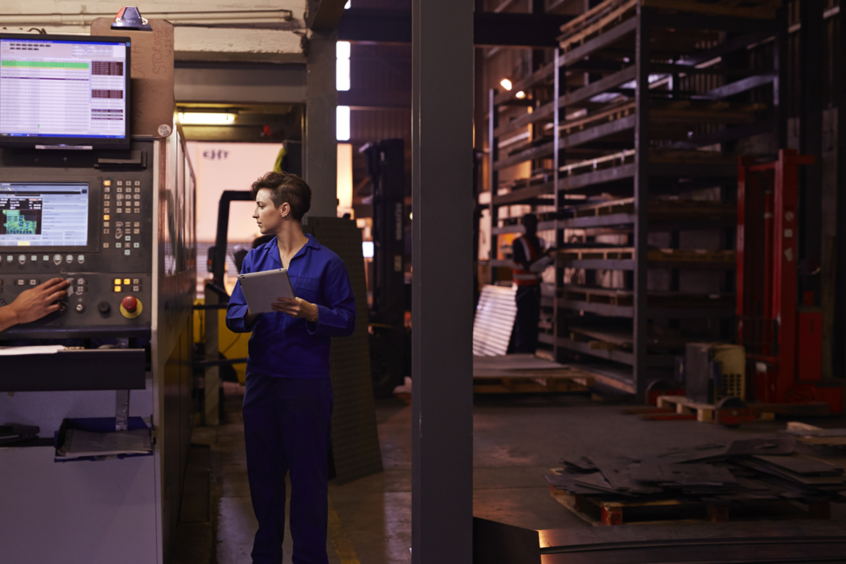 Female steel worker inspecting laser cutter